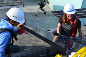 Members of the GRID Alternatives and Elemental teams install solar panels on a roof in Oakland, CA.