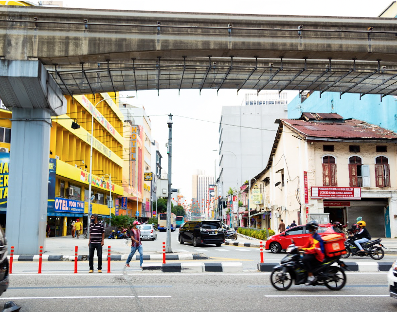 A street in Kuala Lumpur with pedestrians, cyclists and motorists.