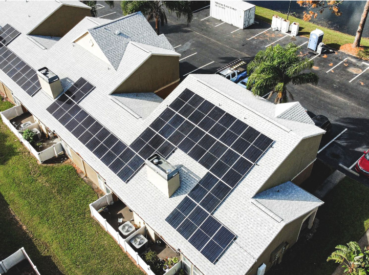 An aerial photograph of solar panels on the roof of a multi-unit building