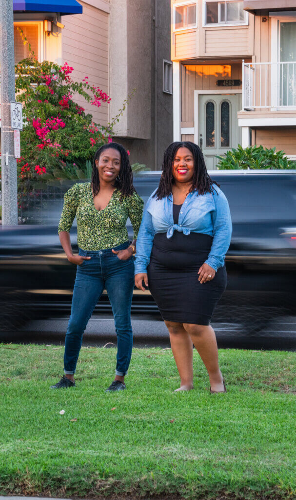Kameale Terry and Evette Ellis stand together smiling, with cars moving past in the background.